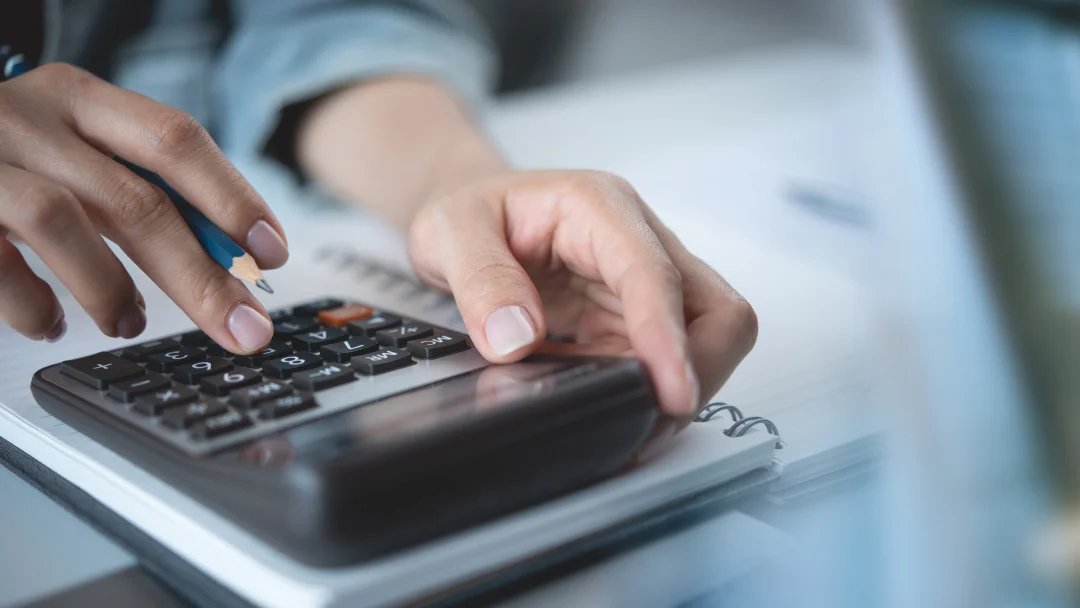 A person calculating expenses on a calculator while creating a budget for better financial management.