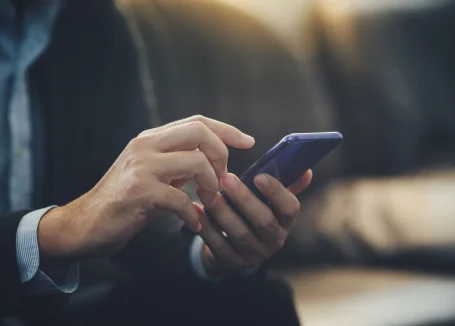 Un homme en costume utilise son téléphone, affichant une expression concentrée et professionnelle.