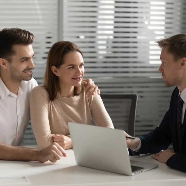 A man and woman discuss financial security with another man in a professional office setting.