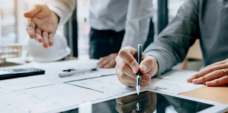 Des professionnels collaborent sur un projet autour d'une table, échangeant des idées et des documents.