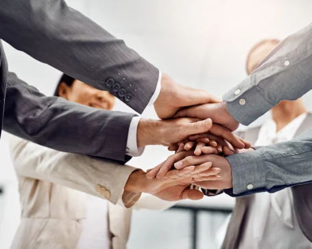  A diverse group of business professionals stacking their hands together, symbolizing teamwork and collaboration in a corporate setting.